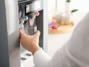 Persona riempie bicchiere d'acqua da un depuratore domestico